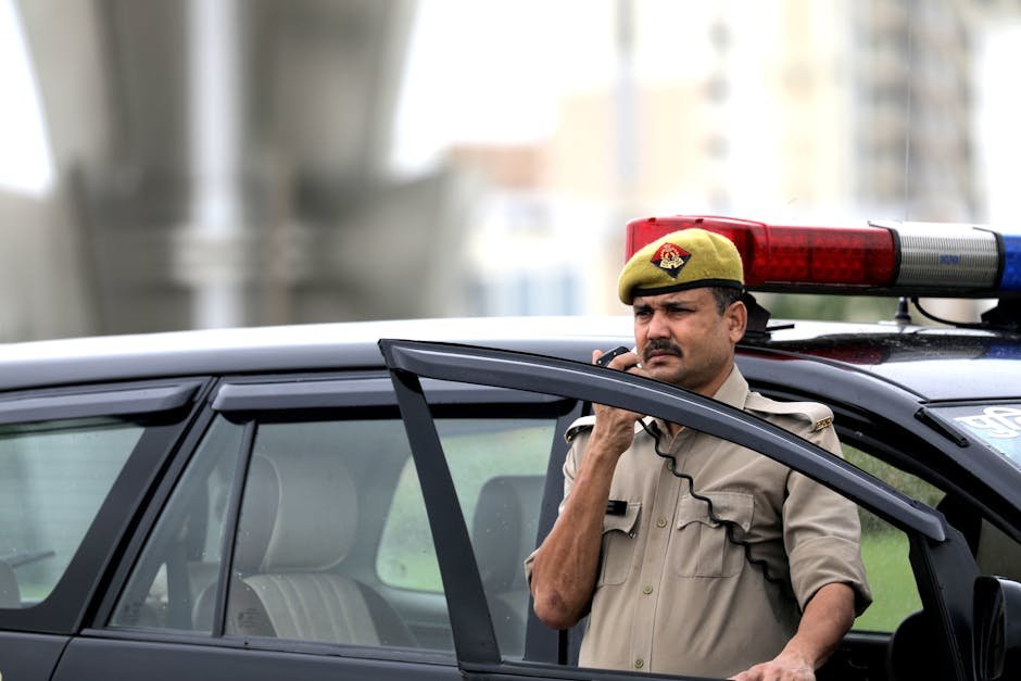 Gurugram Police Mobilise 1,200 Personnel for UPSC Prelims Security Police officer using radio near patrol car outdoors, ensuring public safety.