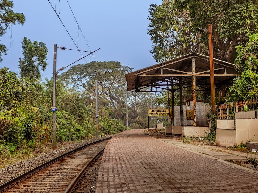Chennai Commuters Brave Elements as Fort Station Foot Overbridge Remains Uncovered Rustic railway platform in Jhaluarber, West Bengal, India amidst lush greenery.
