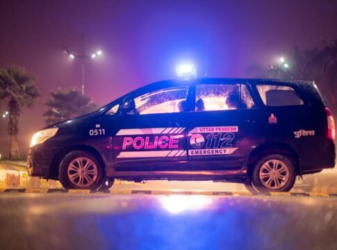 Side view of Uttar Pradesh police car parked at night, illuminated by neon lights and street lamps. Side view of Uttar Pradesh police car parked at night, illuminated by neon lights and street lamps.