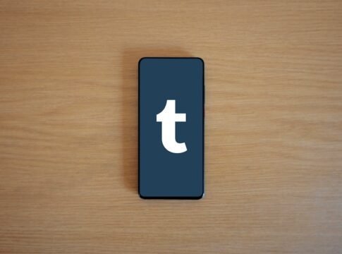 Smartphone displaying app logo on a wooden table, perfect for tech and lifestyle themes.