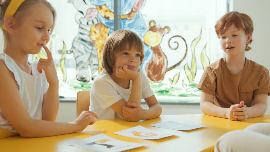 UP Minister Cites Nursery Rhymes as Anti-Cultural, Promotes Lying Three children sitting at a yellow table in a classroom, engaging in a learning activity.