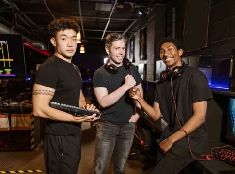 Three friends enjoying a gaming session with high-tech equipment and a joyful atmosphere. Three friends enjoying a gaming session with high-tech equipment and a joyful atmosphere.