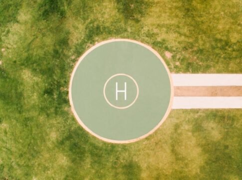 Top-down view of a helipad marked on a grassy field, perfect for aviation themes.