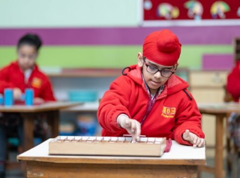 Young boy wearing glasses focused on educational activity in classroom setting.