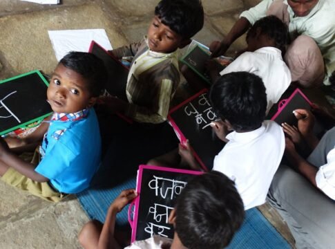 Young students writing on slates in a village school in Melghat, India.