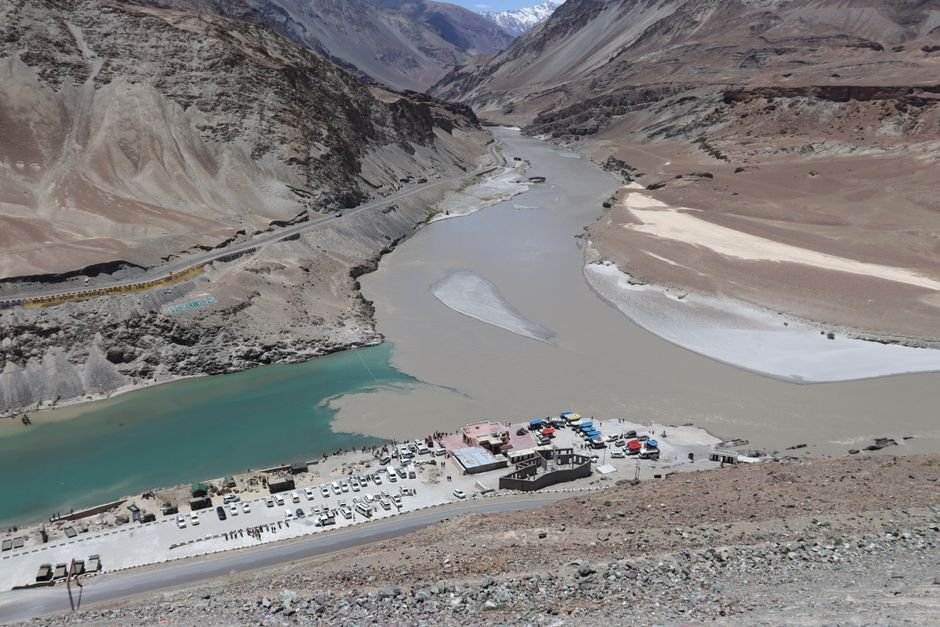 Ladakh Observes Complete Shutdown Amidst Bandh Call by Leh Apex Body and KDA A breathtaking aerial view of a river confluence near Leh surrounded by rugged mountains.