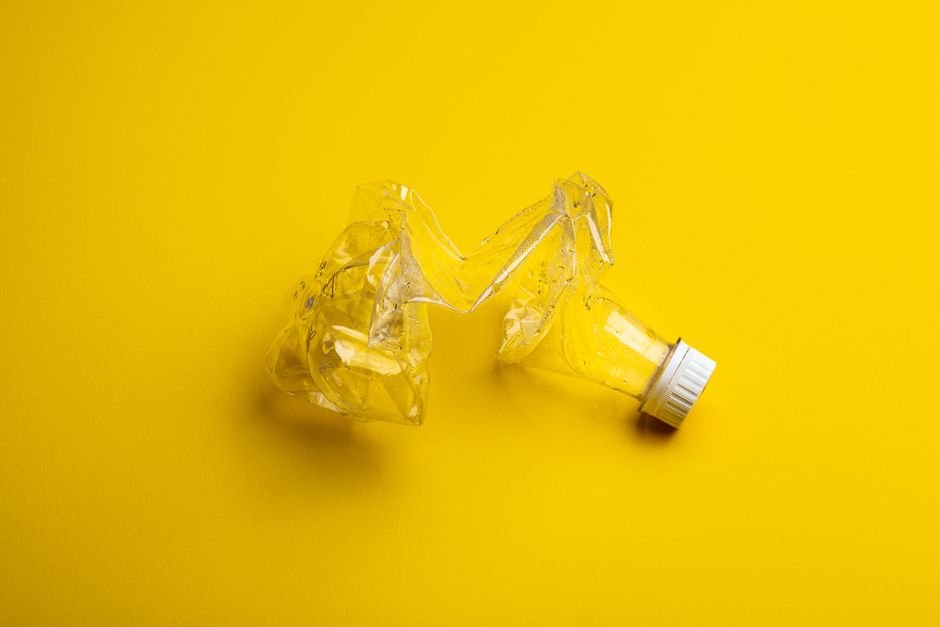 Jammu and Kashmir Assembly Panel Urges Strict Ban on Single-Use Plastics A crumpled plastic bottle against a bright yellow backdrop, highlighting recycling themes.