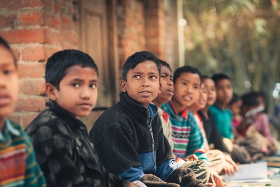 Jammu and Kashmir Delegation Secures Top National Honour at Hyderabad Education Conference A group of children from Bangladesh sitting outdoors, engaged in learning at a rural school.