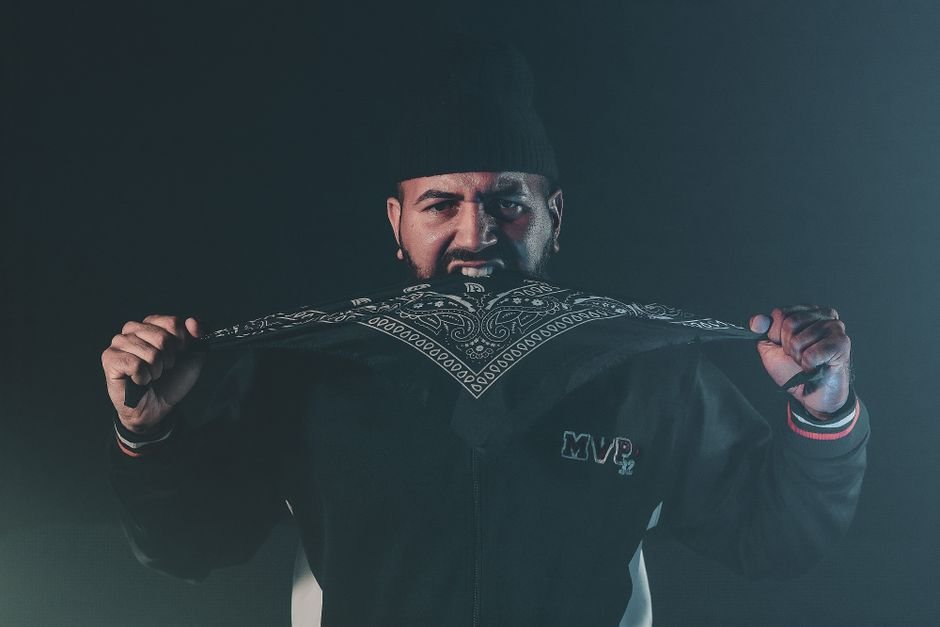 Tamil Nadu Speaker Defends Governor’s Tamil Proficiency Efforts A man intensely holding a patterned bandana in a dark, moody setting.