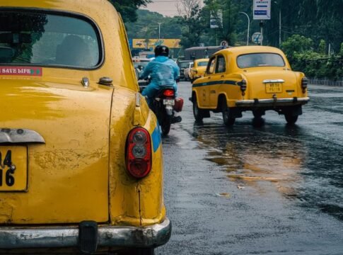 A rainy day scene featuring yellow taxis on a bustling street in Kolkata, India. A rainy day scene featuring yellow taxis on a bustling street in Kolkata, India.