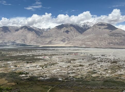 A stunning aerial view of Nubra Valley with mountains and scattered settlements beneath a blue sky.