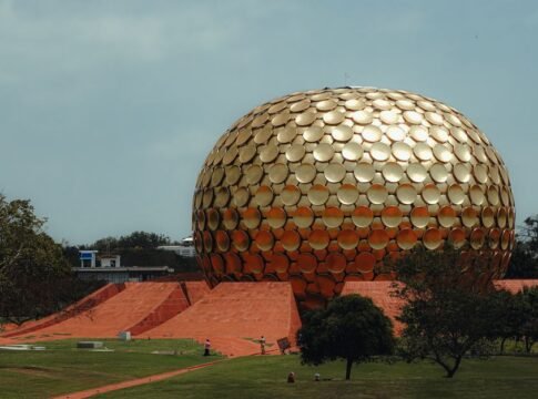 A stunning view of the golden Matrimandir in Auroville, Puducherry, surrounded by lush greenery. A stunning view of the golden Matrimandir in Auroville, Puducherry, surrounded by lush greenery.