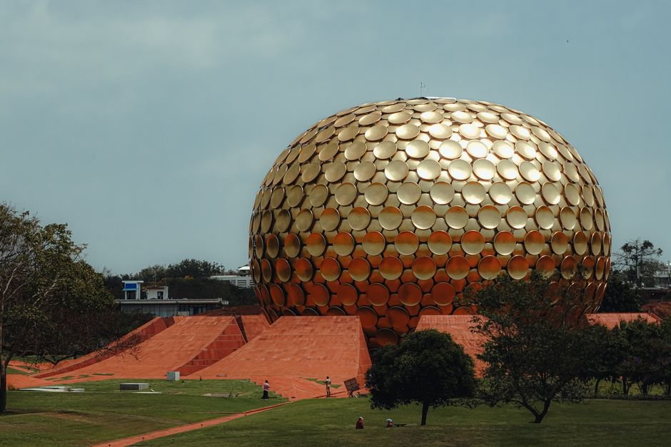 Tamil Nadu Governor Inaugurates Plantation Drive and Lays Foundation Stone for Plaza in Auroville A stunning view of the golden Matrimandir in Auroville, Puducherry, surrounded by lush greenery.