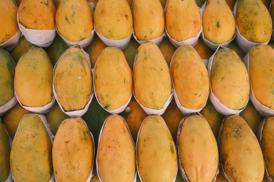 South Indian Farmers Reveal Cherished Mango Varieties A vibrant display of ripe, yellow mangoes neatly arranged in a market setting.
