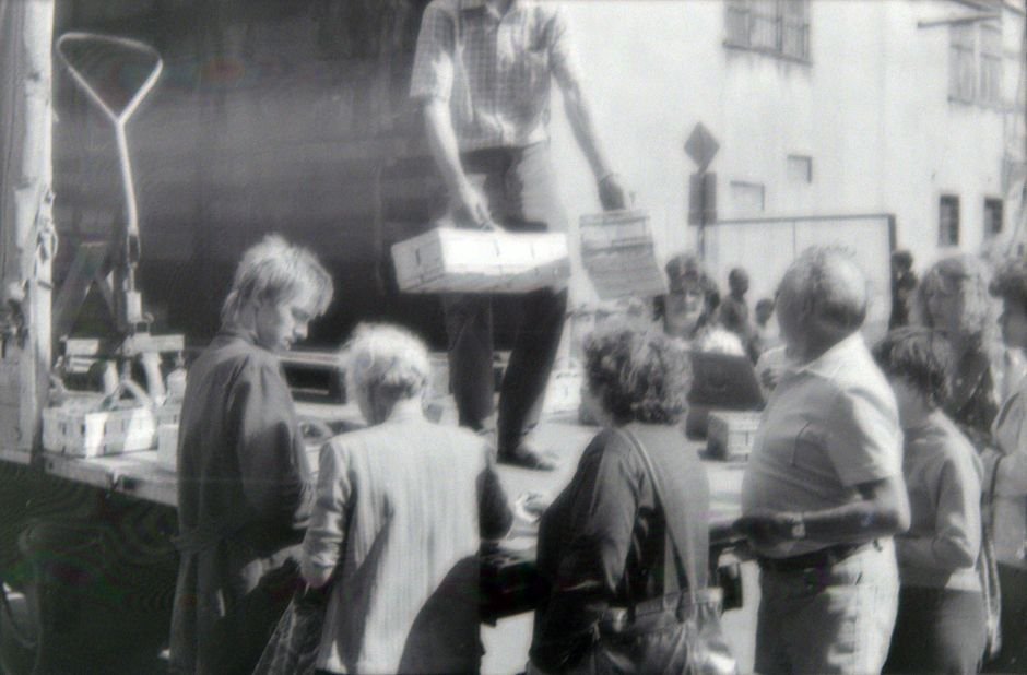 Andhra Pradesh: Buttermilk Distribution Initiative Offers Respite Amidst Scorching Heat A vintage black and white photo showing people gathering at an outdoor market with goods being unloaded.