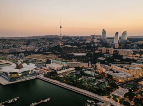Aerial view of Baku's skyline featuring the Flame Towers and Caspian Sea at dusk.