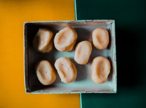 Aerial view of Indian sweets arranged in a decorative box on a colorful background.