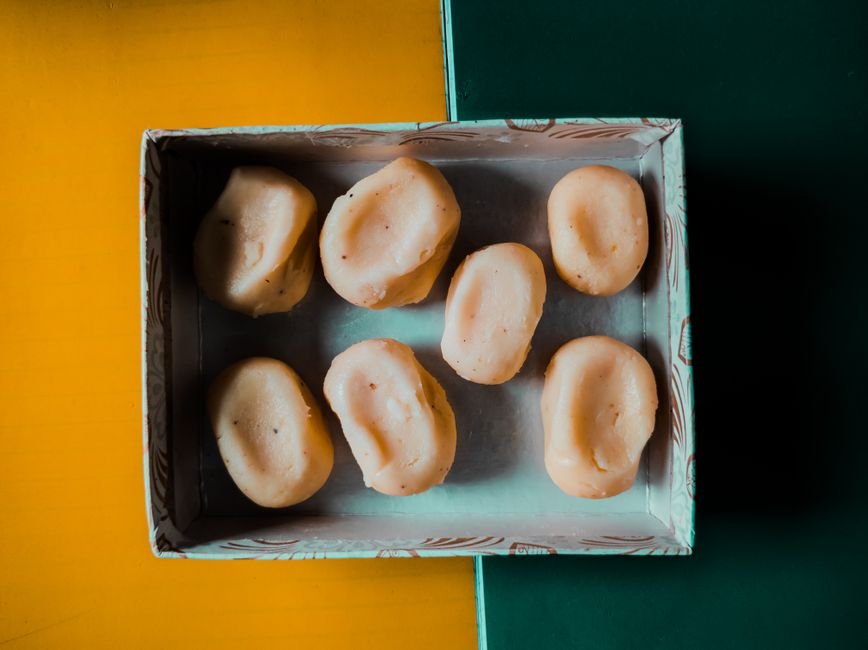 Aerial view of Indian sweets arranged in a decorative box on a colorful background.