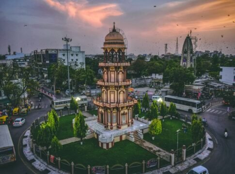 Aerial view of a historic tower in Ahmedabad, India at dusk surrounded by urban cityscape.
