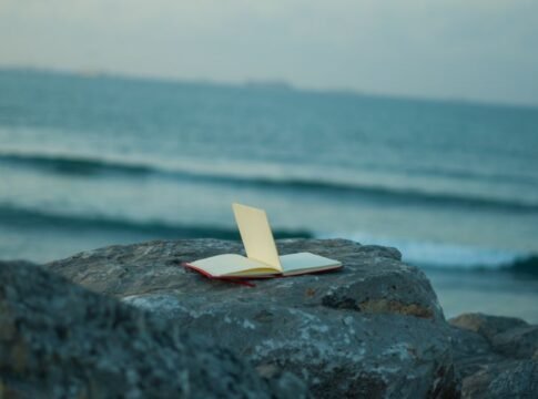 An open notebook rests on a rock by the sea, capturing the serenity of the coastal landscape at sunset. An open notebook rests on a rock by the sea, capturing the serenity of the coastal landscape at sunset.