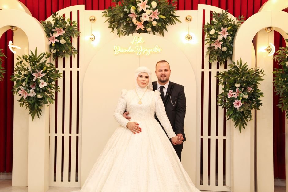 Uttar Pradesh Groom’s ‘Bulldozer Baraat’ Goes Viral, Police Issue Challan Beautiful couple in elegant wedding attire surrounded by floral decor indoors.