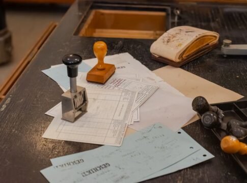 Cluttered desk with office stamps on top of various documents in an office setting.