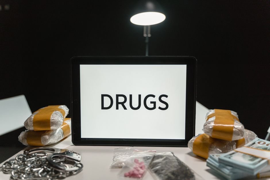 Jammu Division Intensifies Anti-Drug Campaign: 598 FIRs, 701 Arrests in 100 Days Conceptual image of drugs, money, and handcuffs on a table under harsh light, depicting crime themes.