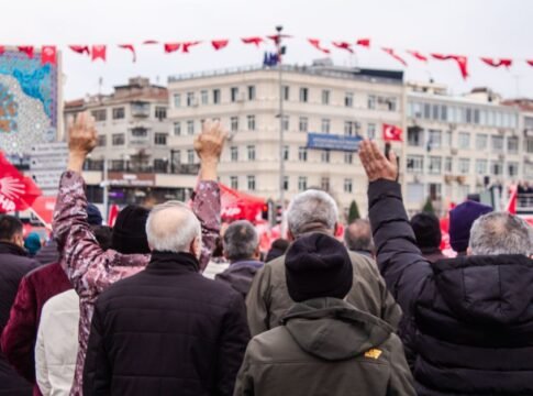 Crowd at a public rally with flags raised, focusing on community spirit and engagement.