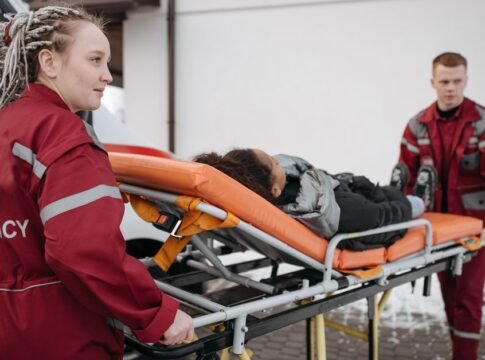 Emergency responders assisting a patient on a stretcher, highlighting teamwork and medical care. Emergency responders assisting a patient on a stretcher, highlighting teamwork and medical care.