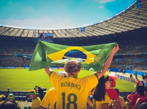Excited Brazilian fans holding flag at soccer match in vibrant stadium atmosphere. Excited Brazilian fans holding flag at soccer match in vibrant stadium atmosphere.