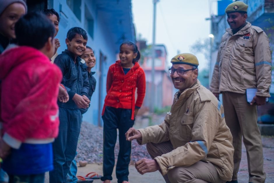 Mortar-Like Object Found Near River in Kanpur Dehat Prompts Bomb Squad Response Friendly police officers interacting with smiling children in a street in Uttar Pradesh, India.
