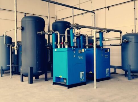 Industrial air compressor setup with blue tanks and pipes inside a plant.