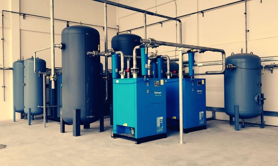 JAKSON Engineers Appoints Alexey Ustinov as Independent Director Industrial air compressor setup with blue tanks and pipes inside a plant.