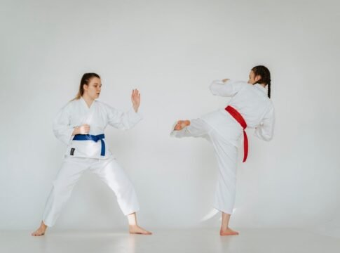 Karate sparring practice with two young women showcasing skill and technique in traditional attire.