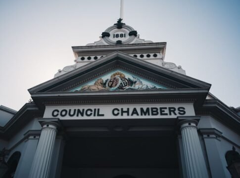 Low angle view of a historic neoclassical council chambers facade with columns and ornate detailing. Low angle view of a historic neoclassical council chambers facade with columns and ornate detailing.