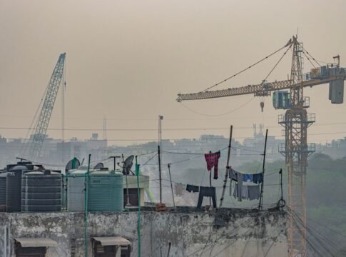 Rooftop view in New Delhi featuring a construction crane and clothes drying in an urban setting. Rooftop view in New Delhi featuring a construction crane and clothes drying in an urban setting.
