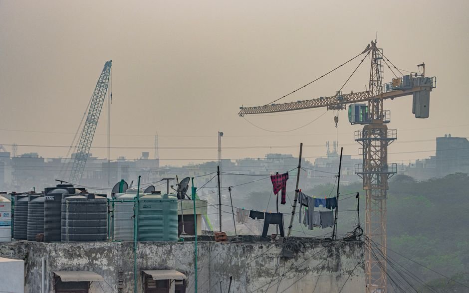 Rooftop view in New Delhi featuring a construction crane and clothes drying in an urban setting.