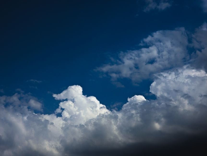 Stunning cumulonimbus clouds form a dramatic scene against a deep blue sky, capturing nature's beauty.