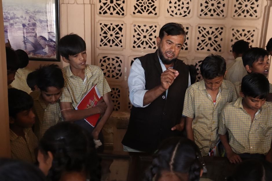 Maharashtra Zilla Parishad Teachers Fall Short on TET Qualification: Four in Five Unqualified Teacher guiding attentive students during an interactive indoor lesson, fostering education.