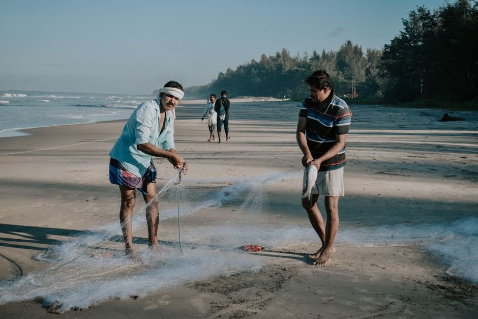 Two fishermen casting nets on a tranquil beach during the day. Perfect for lifestyle and travel themes.