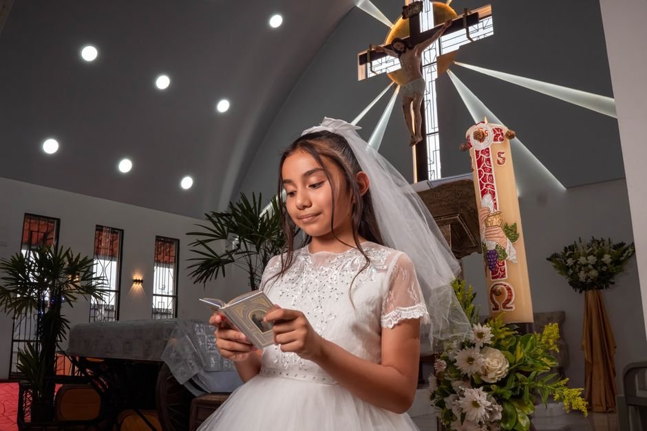 Pope Francis’s Longstanding Friendship with Spanish Engineer Revealed Young girl in white dress reading during communion ceremony in church.