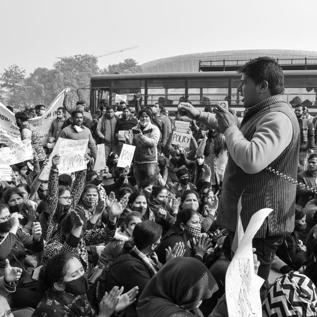 Uttar Pradesh: SP Chief Akhilesh Yadav Slams BJP Over University Demolition Notice A black and white image capturing a protest crowd with a passionate speaker addressing the gathering.