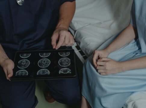 A doctor shows and explains brain scan images to a patient in a medical setting.