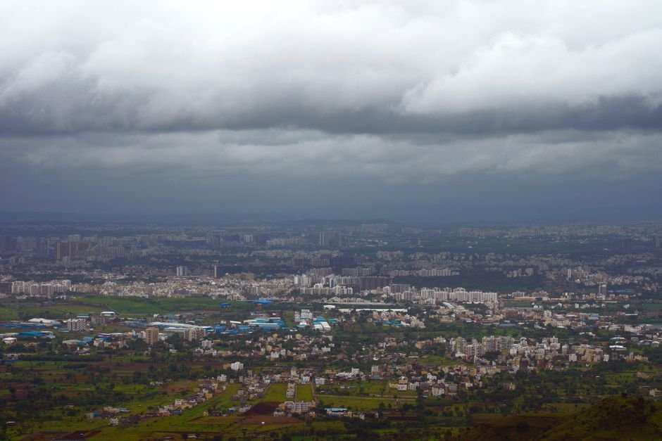 Pune Implements Heavy Vehicle Ban Amid Monsoon to Prevent Traffic Gridlock A dramatic aerial view of Pune, India, showcasing urban sprawl under stormy clouds.