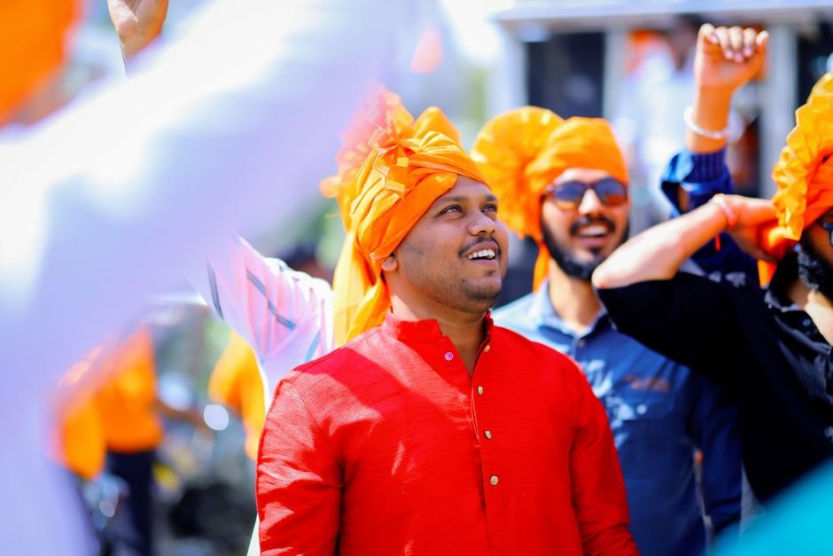 A joyful group of men celebrating outdoors in Malegaon, India, wearing bright turbans.