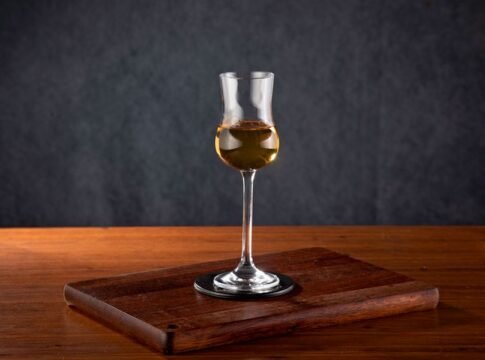 A sophisticated tall glass of wine on a rustic wooden table, perfect for luxury dining settings. A sophisticated tall glass of wine on a rustic wooden table, perfect for luxury dining settings.