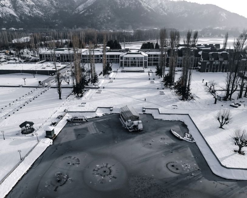 Jammu and Kashmir: University of Kashmir Achieves UGC Category-I Status A stunning aerial view of a frozen Dal Lake with snow-covered scenery in Srinagar, Kashmir.