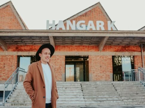 A stylish man with a hat in front of the iconic Hangar K building. A stylish man with a hat in front of the iconic Hangar K building.