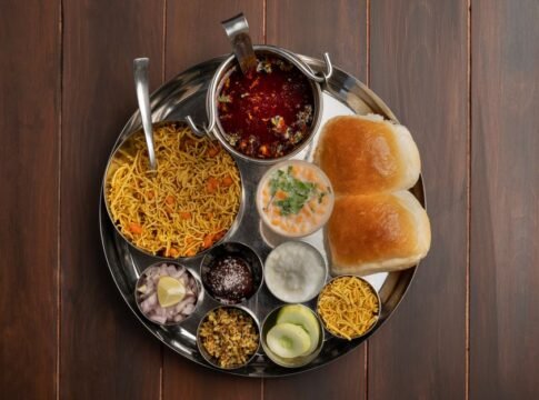 A top view of a traditional Maharashtra thali featuring spicy pav bhaji, vegetables, and condiments in Pune, India. A top view of a traditional Maharashtra thali featuring spicy pav bhaji, vegetables, and condiments in Pune, India.
