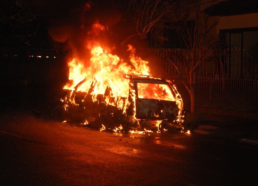 Bengaluru Garage Fire Destroys Over 25 Vehicles, Including Luxury Cars A vehicle is completely engulfed in flames, casting a dramatic glow on a dark street.